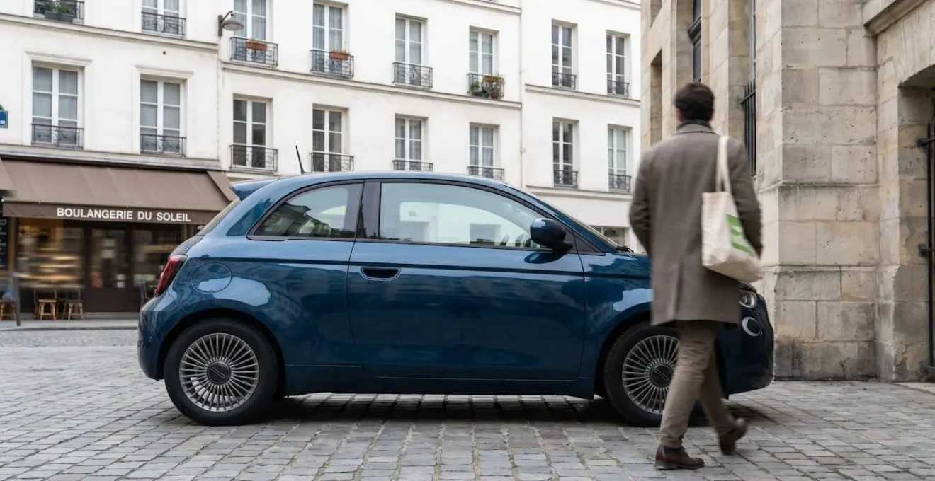 Citadine moderne garée dans une rue urbaine française le matin avec une personne s'éloignant du véhicule